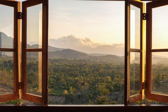 View from the window to the fields and mountains at sunset. View from the hotel window in the north of Bali